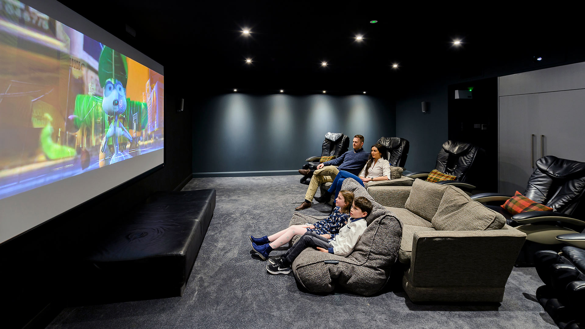 Family in a private cinema room watching cartoon on screen at Cork International Hotel