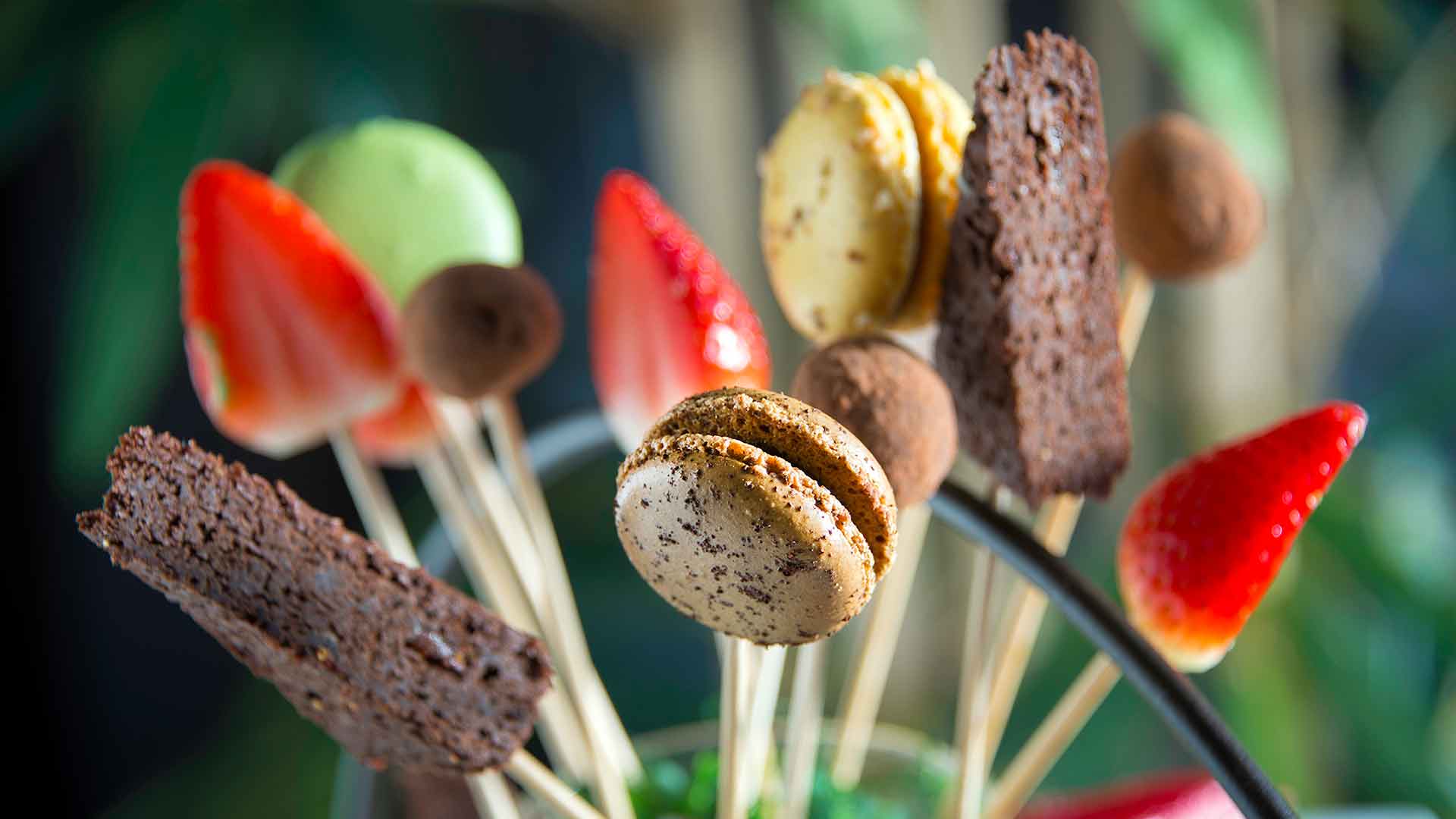 Macaroons, chocolate treats and strawberries arranged on skewers