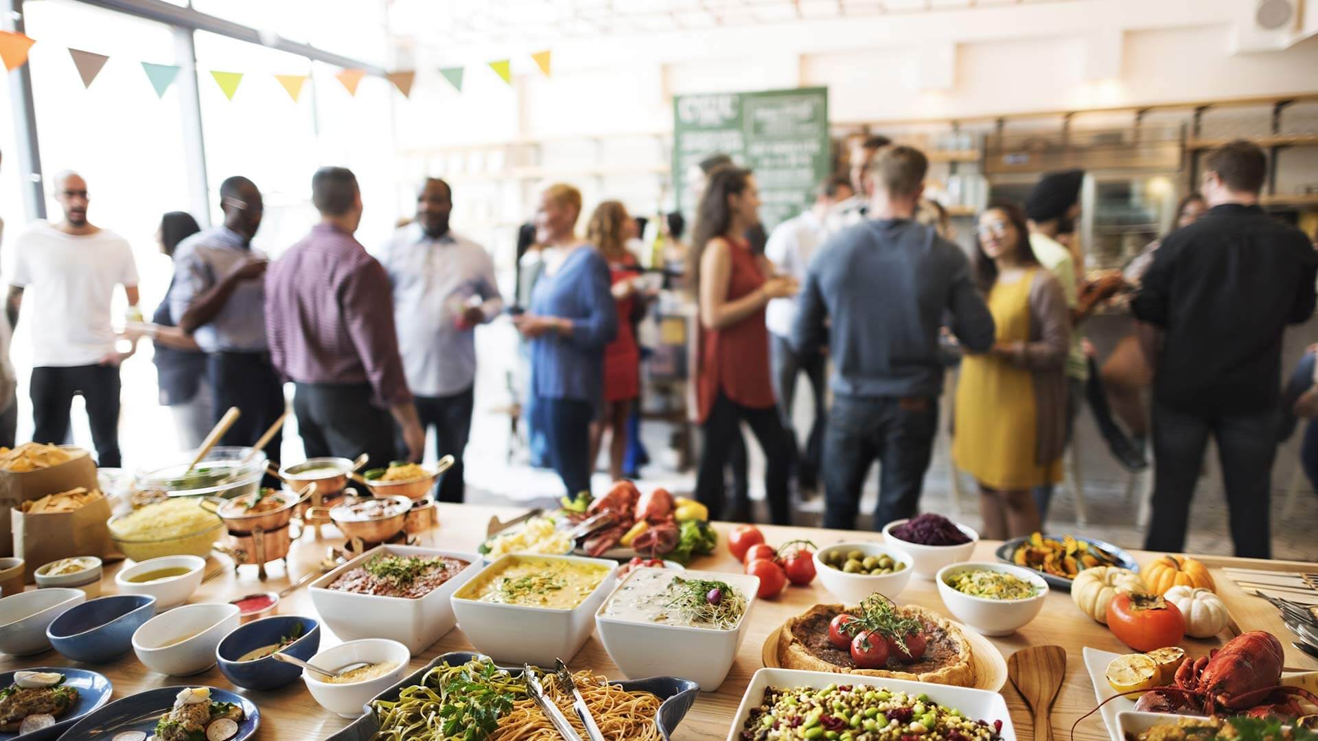 People at a party with a selection of food, dips and snacks on a table