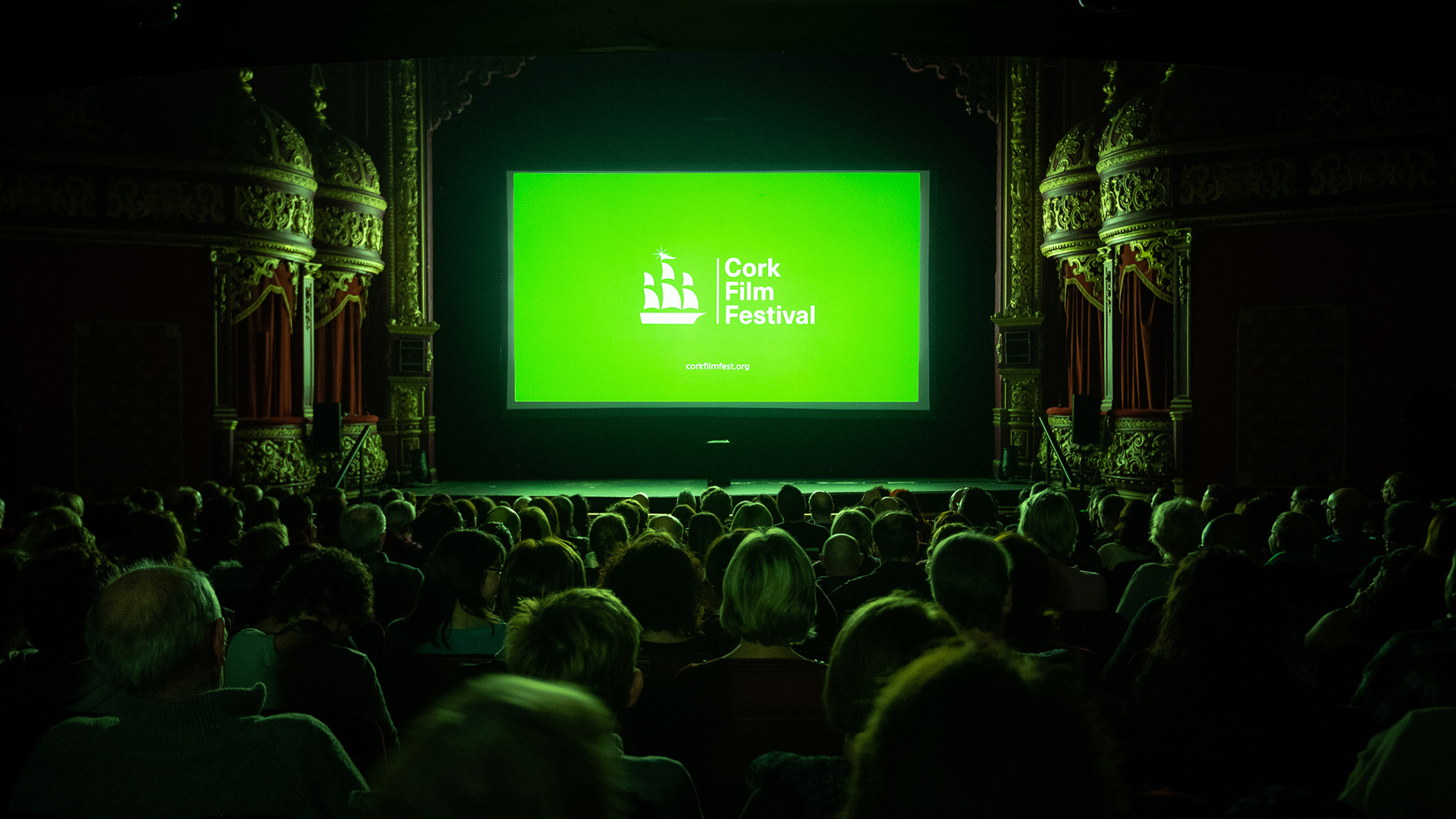 Audience in theater watching screen displaying Cork Film Festival